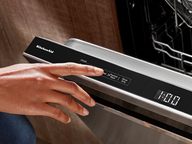 Person selecting a wash cycle on a top control dishwasher