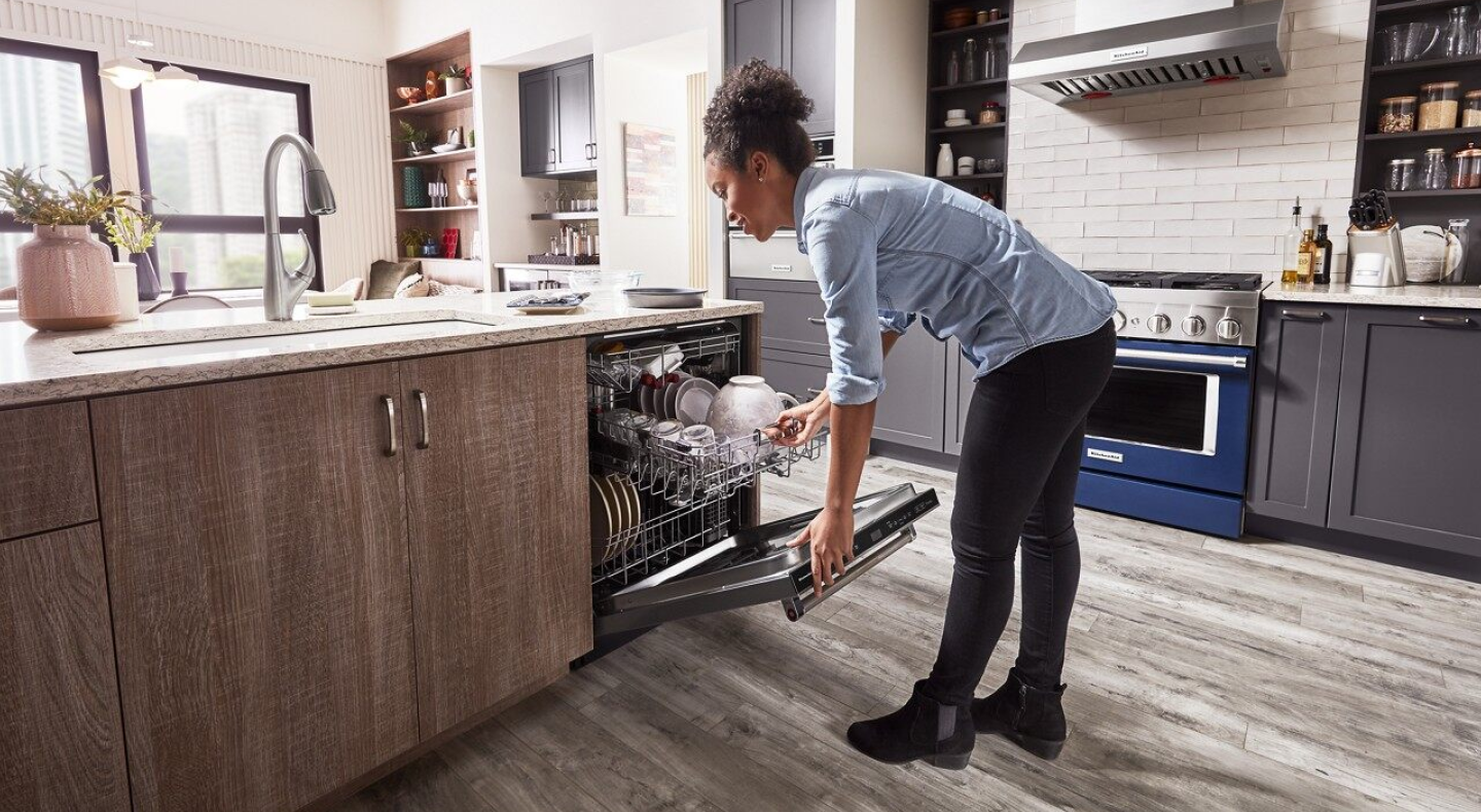 Woman closing a loaded dishwasher Woman closing a loaded dishwasher