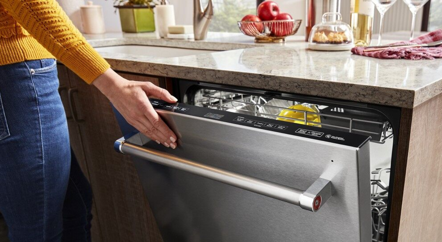 Person closing a stainless steel top control dishwasher Person closing a stainless steel top control dishwasher