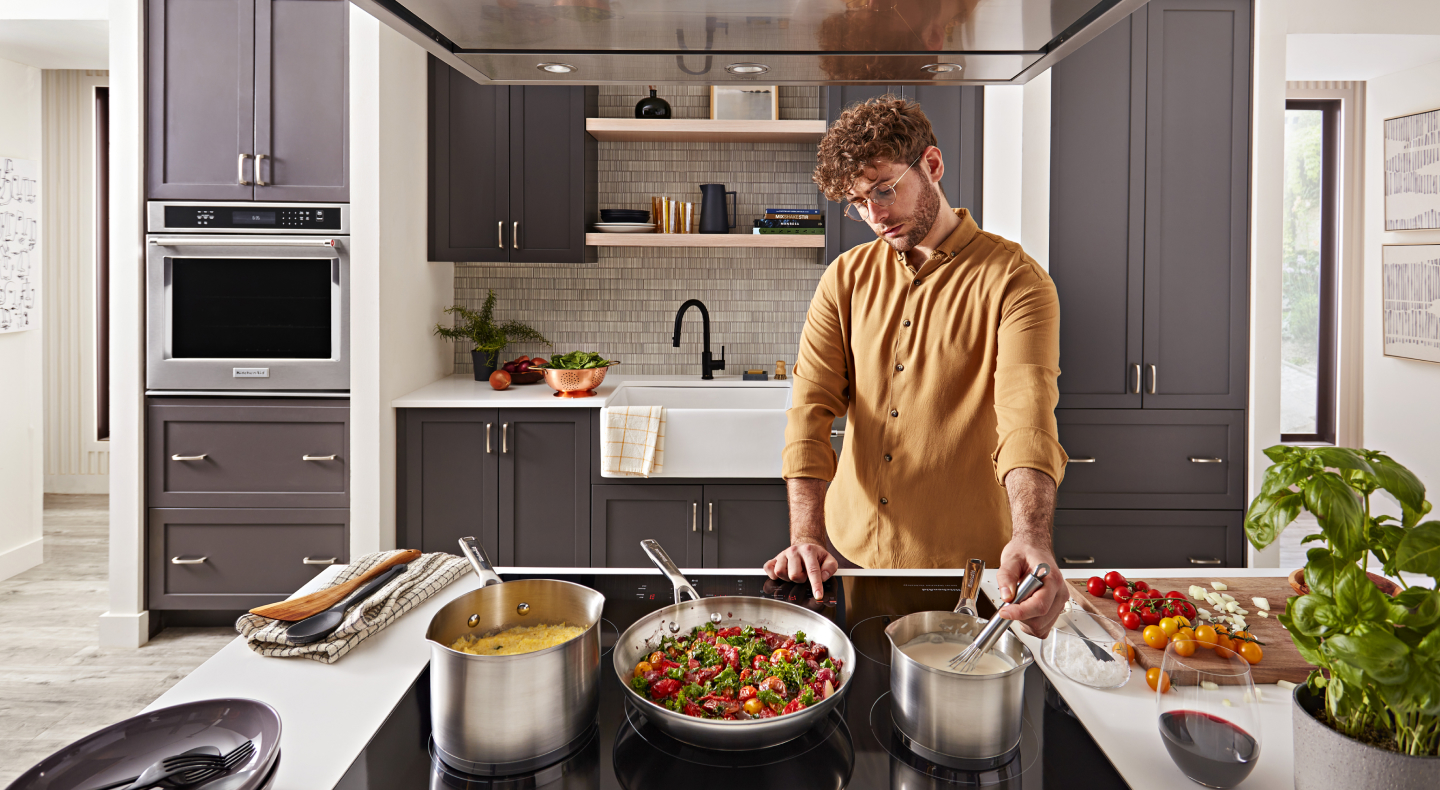 Person whisking food on the stovetop next to several cooking dishes Person whisking food on the stovetop next to several cooking dishes