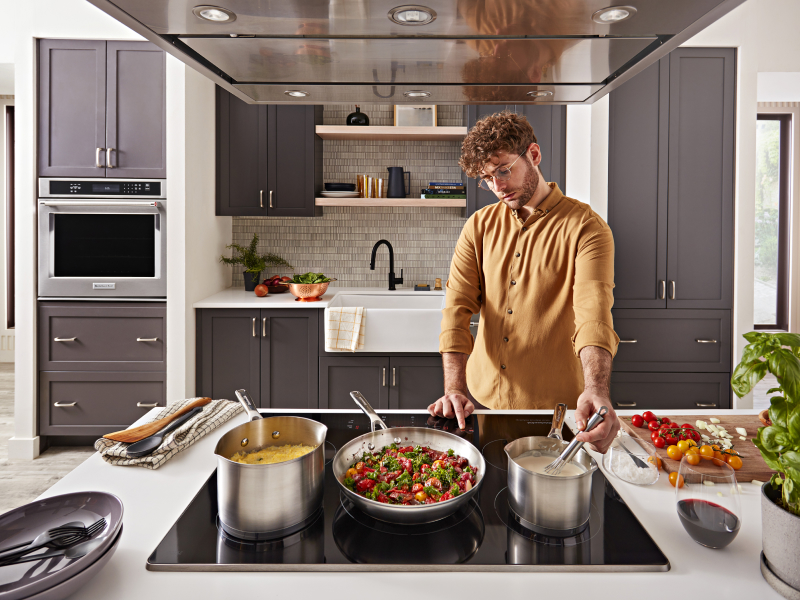 Person whisking food on the stovetop next to several cooking dishes Person whisking food on the stovetop next to several cooking dishes