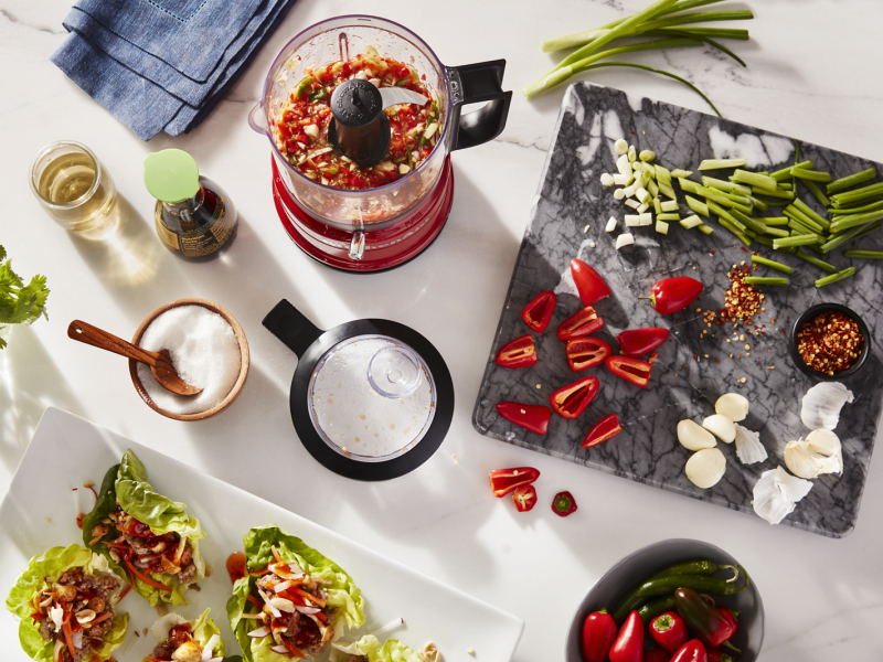 Vegetables and herbs on a cutting board and in a food processor