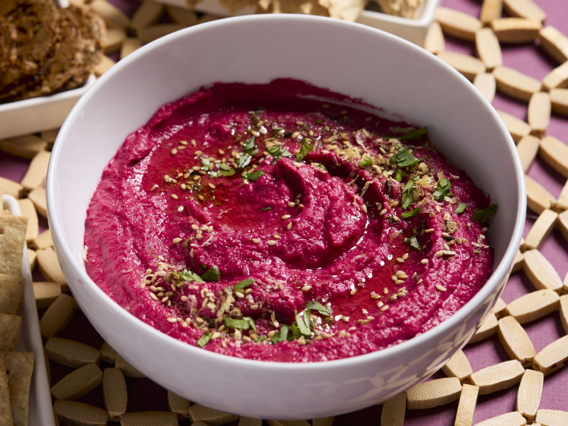 Beet hummus topped with herbs in a white bowl Beet hummus topped with herbs in a white bowl