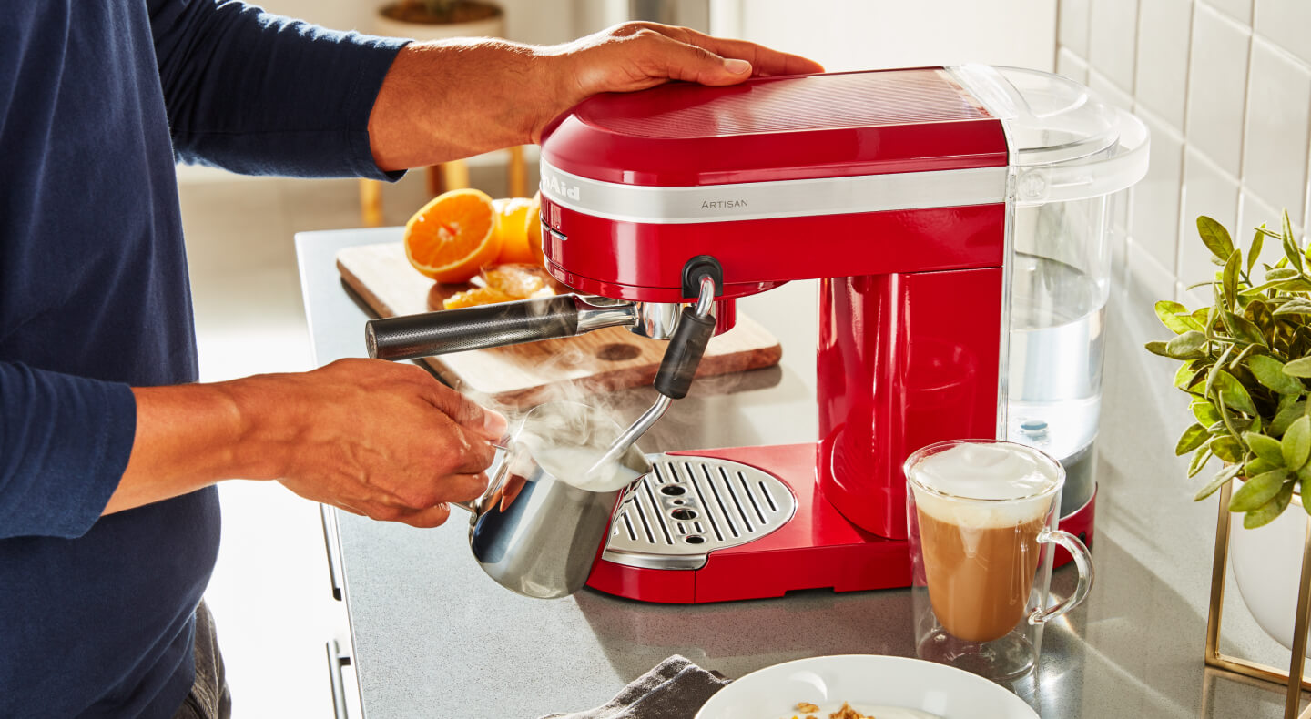 Man frothing milk with a red espresso machine