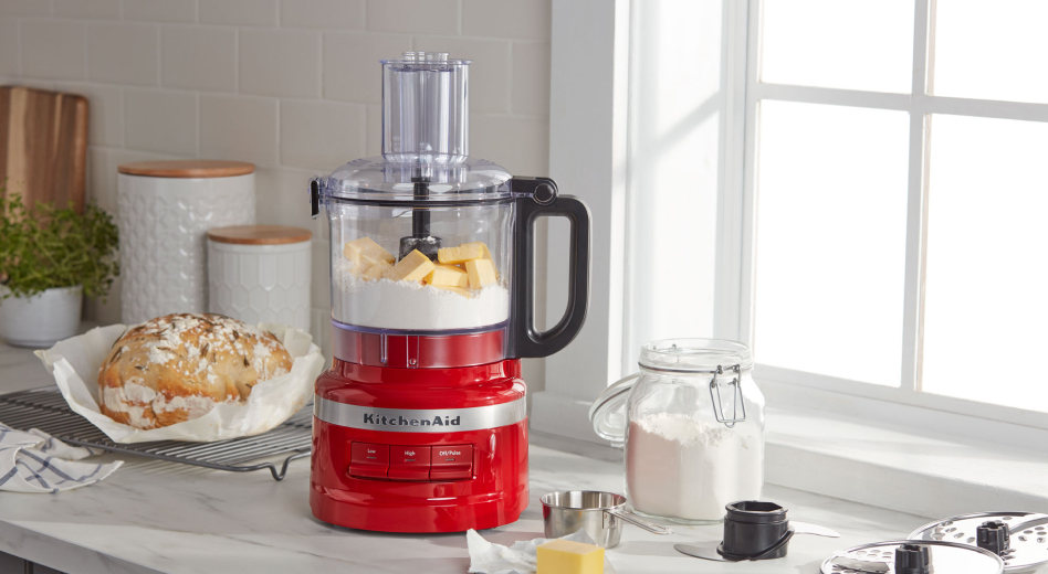 A KitchenAid® food processor with butter and flour in the bowl, sitting on a kitchen counter next to a fresh loaf of bread. A KitchenAid® food processor with butter and flour in the bowl, sitting on a kitchen counter next to a fresh loaf of bread.