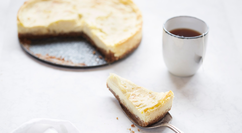 A piece of custard crumb pie on a pie server next to a cup of tea and the rest of the pie. A piece of custard crumb pie on a pie server next to a cup of tea and the rest of the pie.