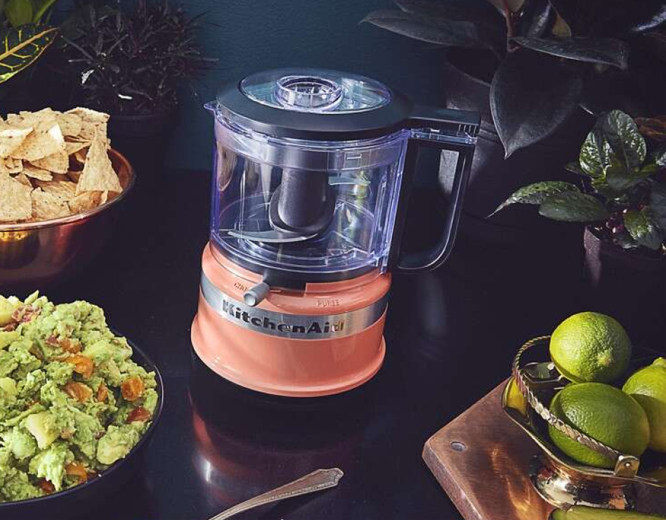 Coral food chopper next to bowl of guacamole and limes Coral food chopper next to bowl of guacamole and limes