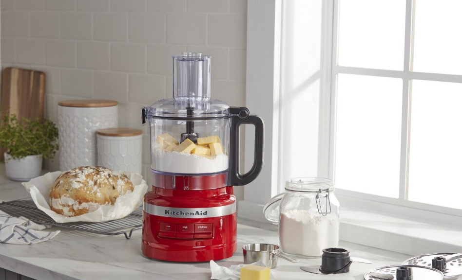 Red food processor with butter and flour next to a loaf of bread Red food processor with butter and flour next to a loaf of bread