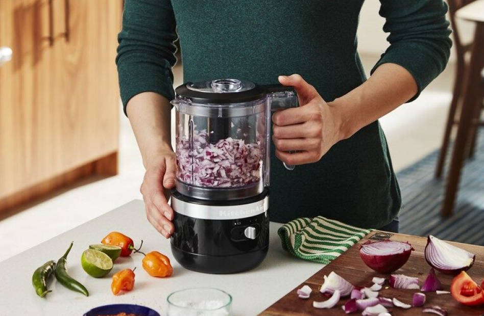 Woman chopping red onions with a black cordless food chopper Woman chopping red onions with a black cordless food chopper