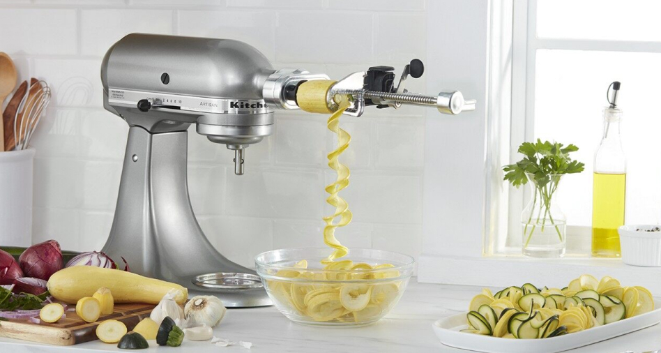 Silver KitchenAid brand stand mixer with zucchini in the spiralizing attachment Silver KitchenAid brand stand mixer with zucchini in the spiralizing attachment