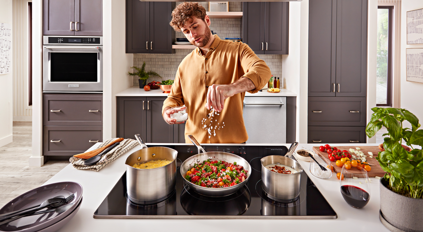 Person adding seasoning to a pan Person adding seasoning to a pan