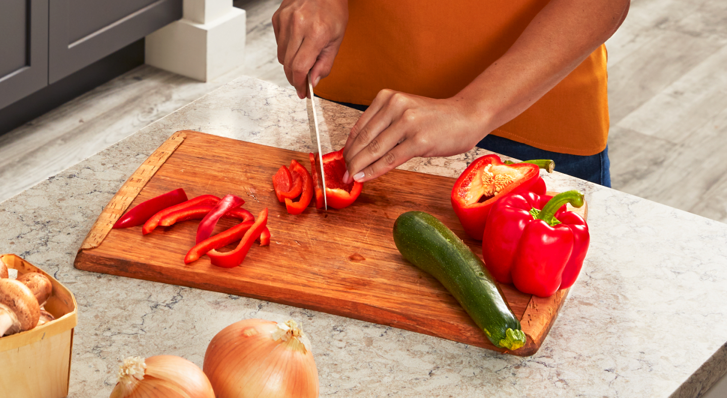 Person slicing bell pepper on a cutting board Person slicing bell pepper on a cutting board
