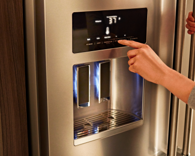 Person adjusting temperature settings on a refrigerator display 