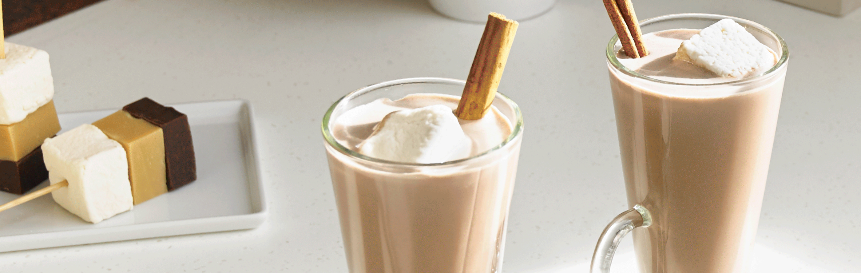 Coffee beverage in glass mugs garnished with marshmallows and cinnamon