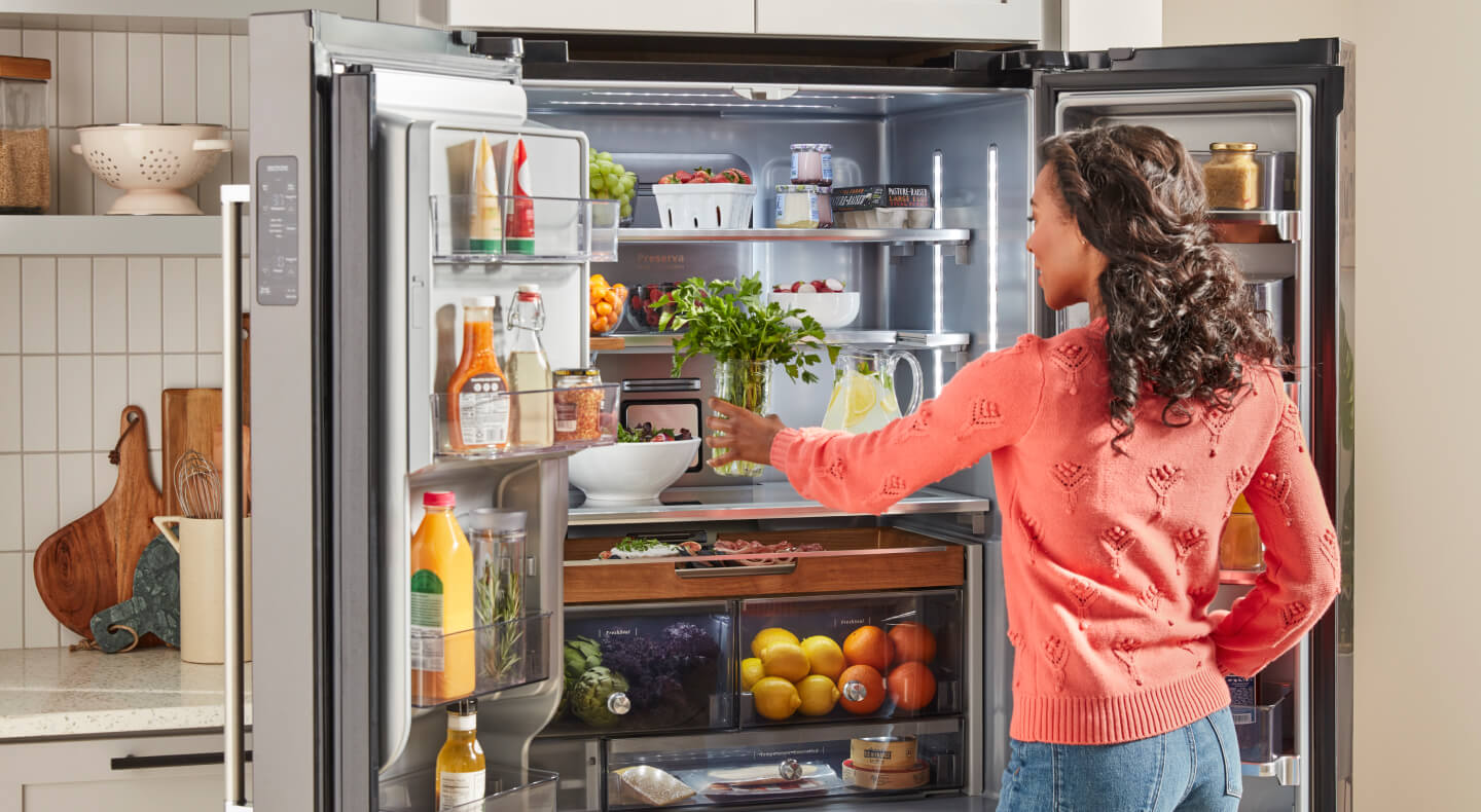 A person putting a jar with herbs in an open French door refrigerator