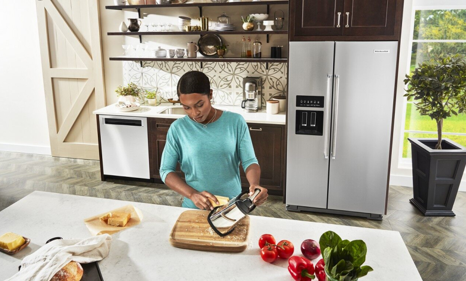 Woman grating cheese in front of a side by side refrigerator Woman grating cheese in front of a side by side refrigerator