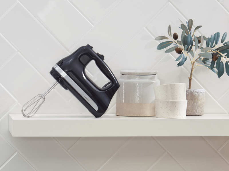 Coral colored KitchenAid® hand mixer standing on countertop with copper bowl filled with whipped cream Coral colored KitchenAid® hand mixer standing on countertop with copper bowl filled with whipped cream