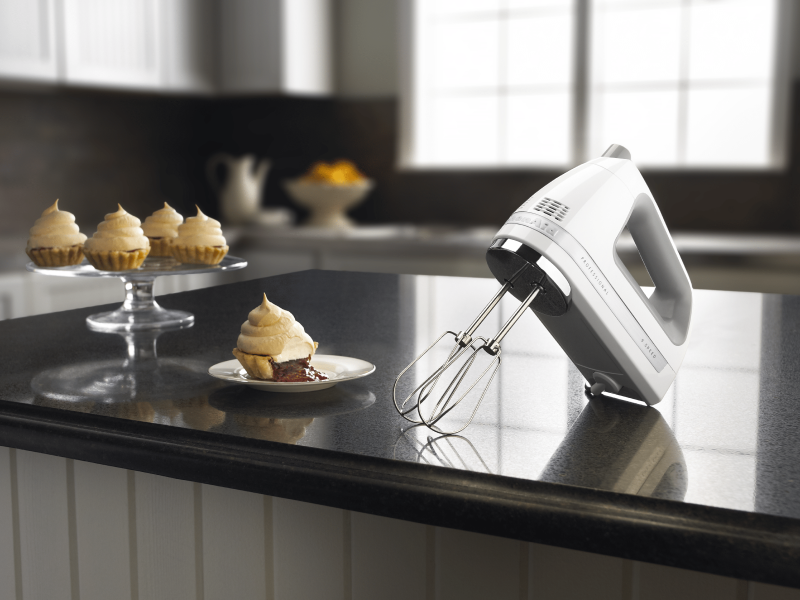 Stainless steel KitchenAid® hand mixer on countertop with cream-topped mini pie desserts Stainless steel KitchenAid® hand mixer on countertop with cream-topped mini pie desserts