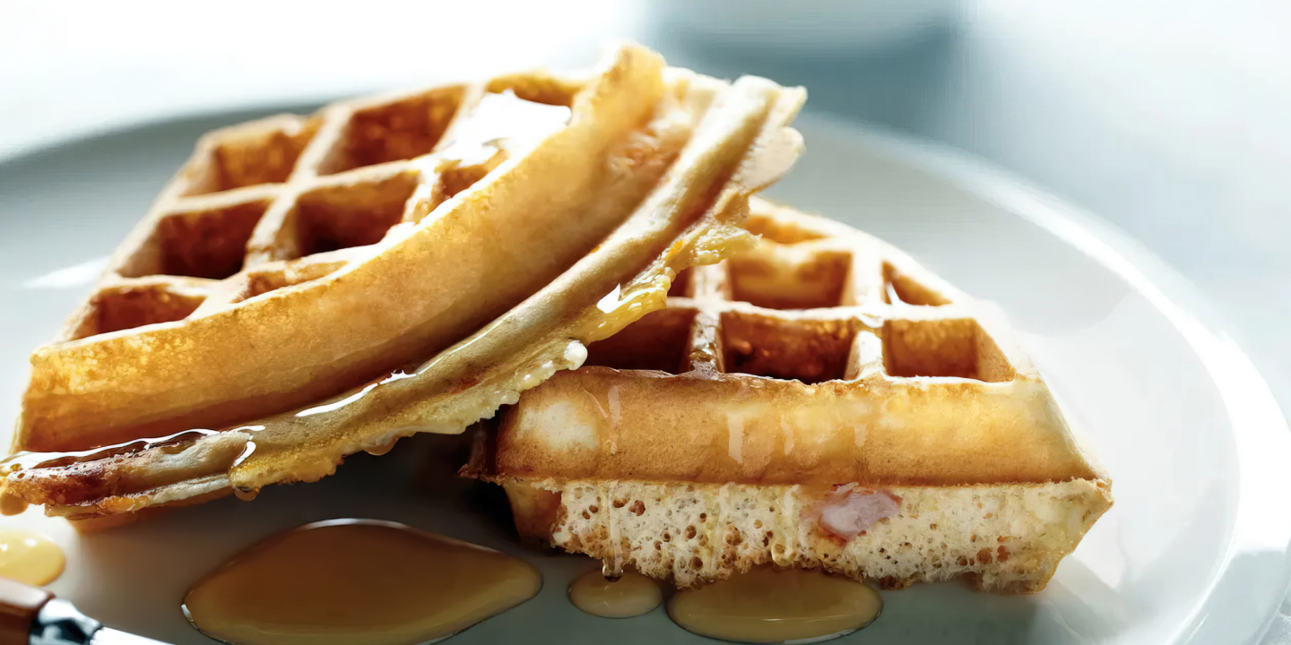 Two quarters of waffles sitting on a plate, drizzled with syrup.  Two quarters of waffles sitting on a plate, drizzled with syrup.