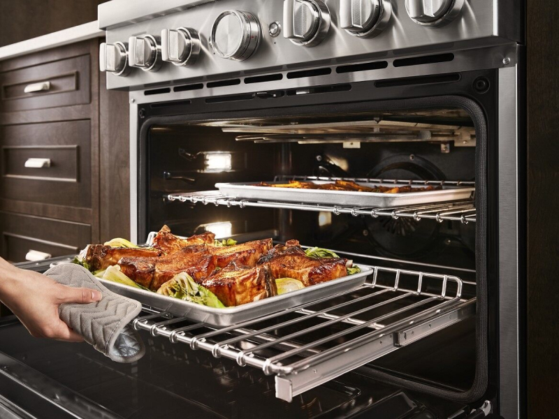 Roasted meats and vegetables being removed from oven