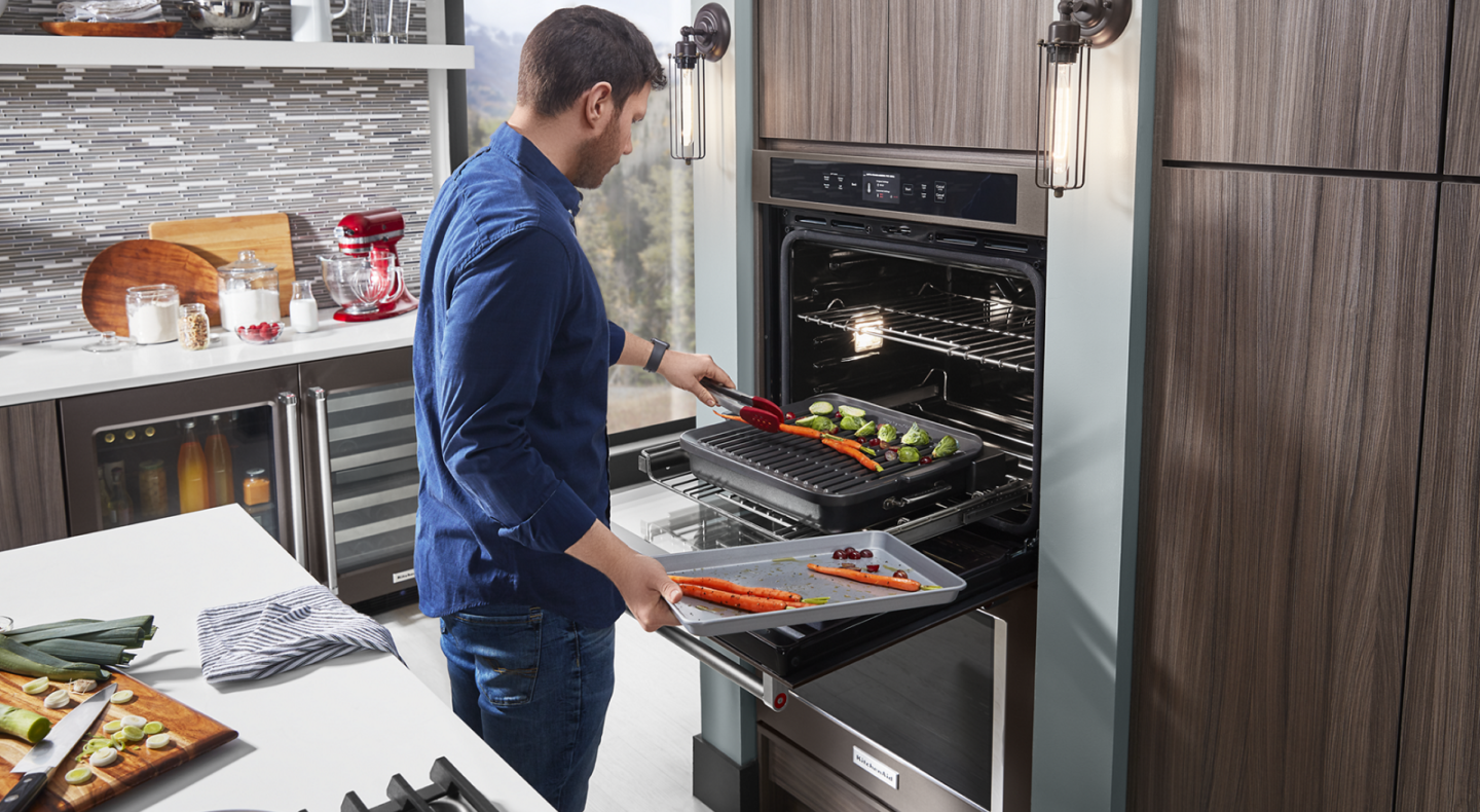 Man roasting vegetables in KitchenAid® Smart Oven+ with Grill Attachment