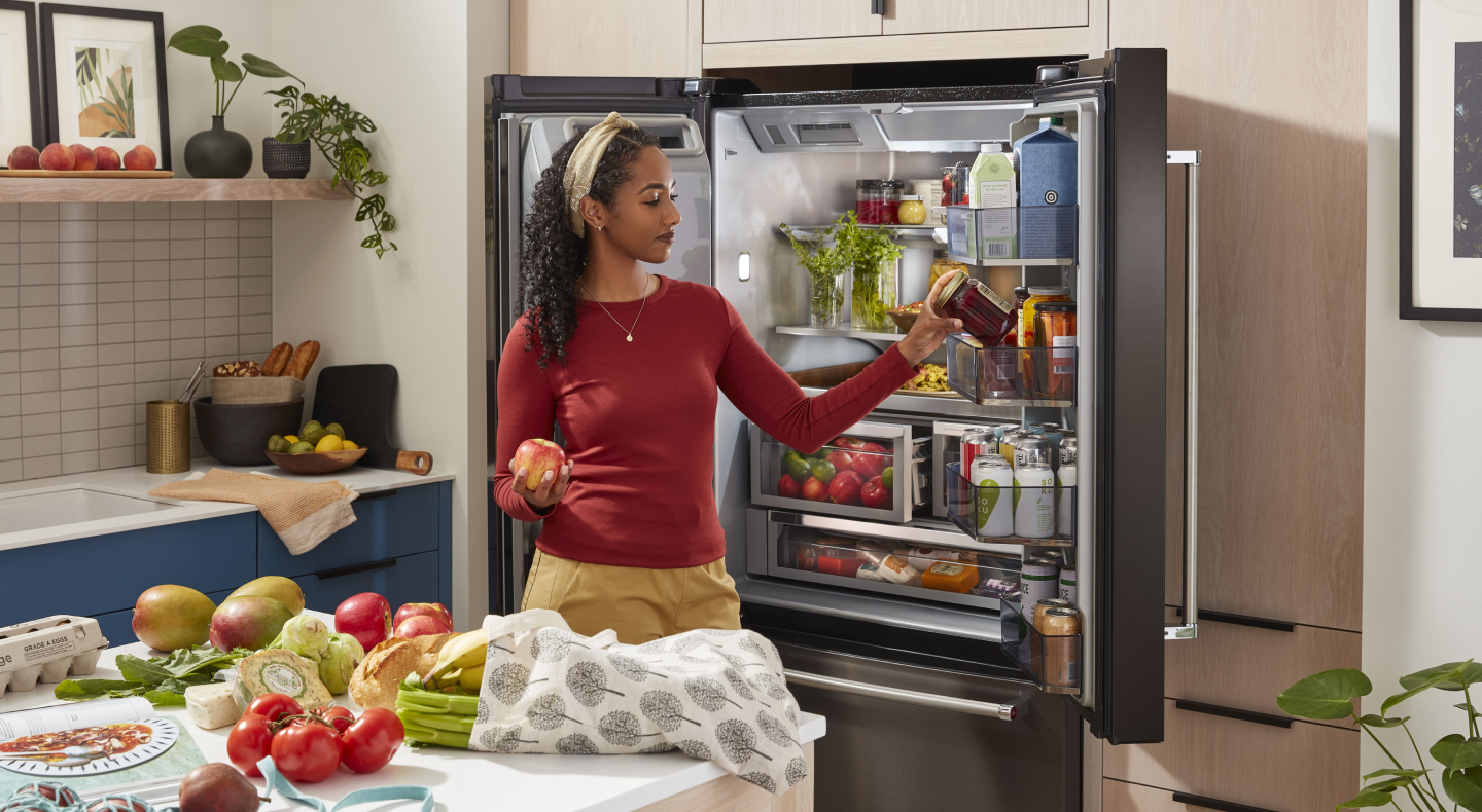 Person putting items in a KitchenAid® French door refrigerator near ingredients on counter Person putting items in a KitchenAid® French door refrigerator near ingredients on counter