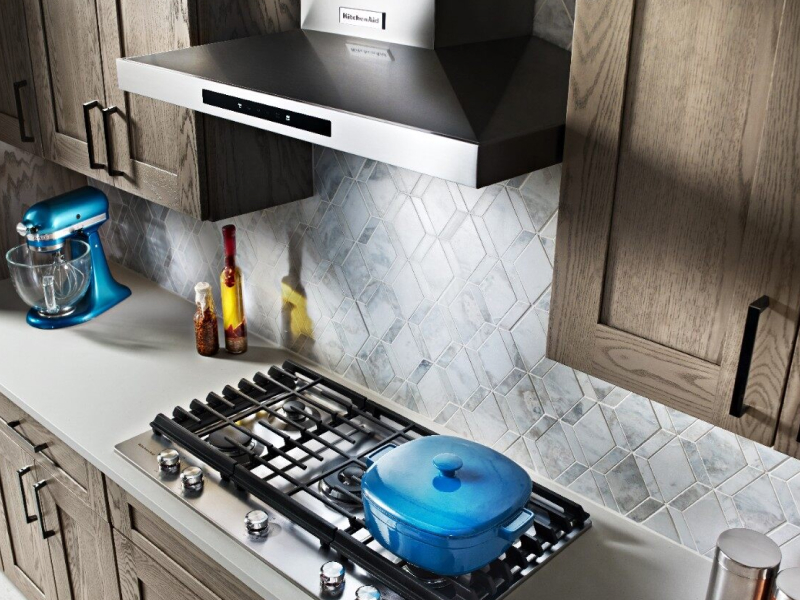 KitchenAid® wall mount range hood above gas stovetop with a blue pot