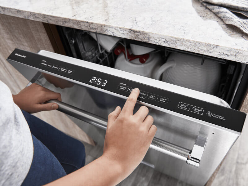 Person selecting settings on a top-control dishwasher from KitchenAid brand