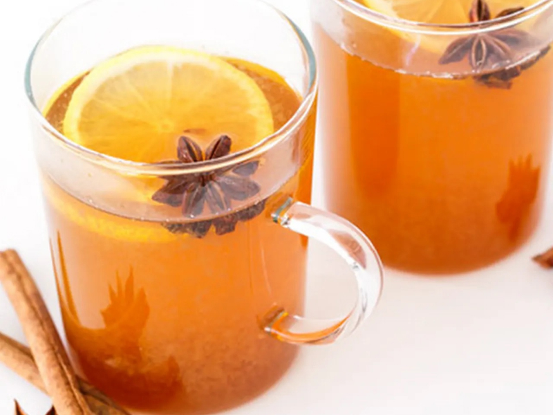 Two glass mugs of black tea with lemon and spices
