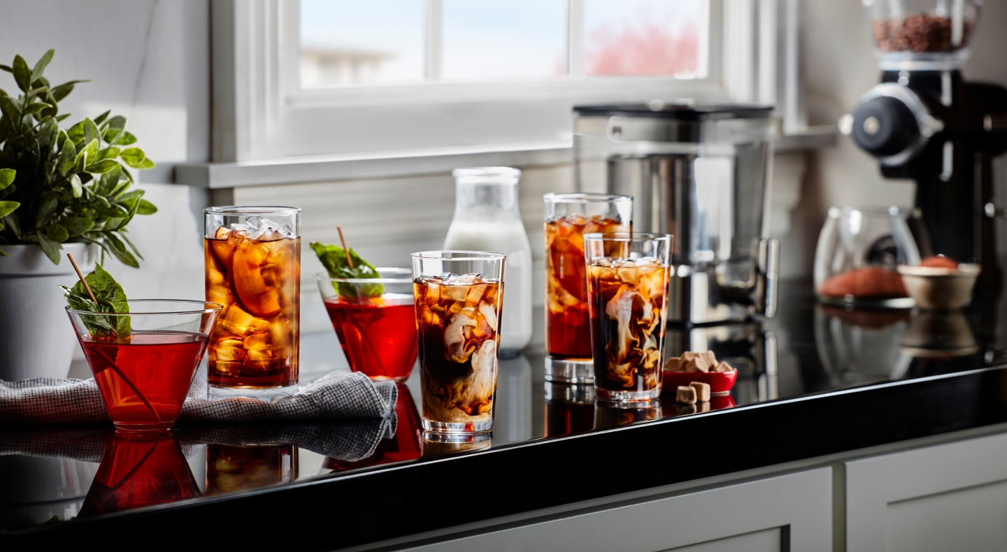 Glasses of iced black tea with peach slices and iced herbal tea with mint garnishes Glasses of iced black tea with peach slices and iced herbal tea with mint garnishes