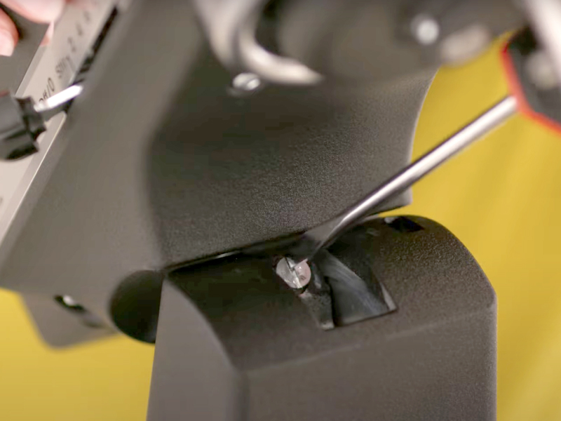 A person adjusting a black tilt-head stand mixer with a flathead