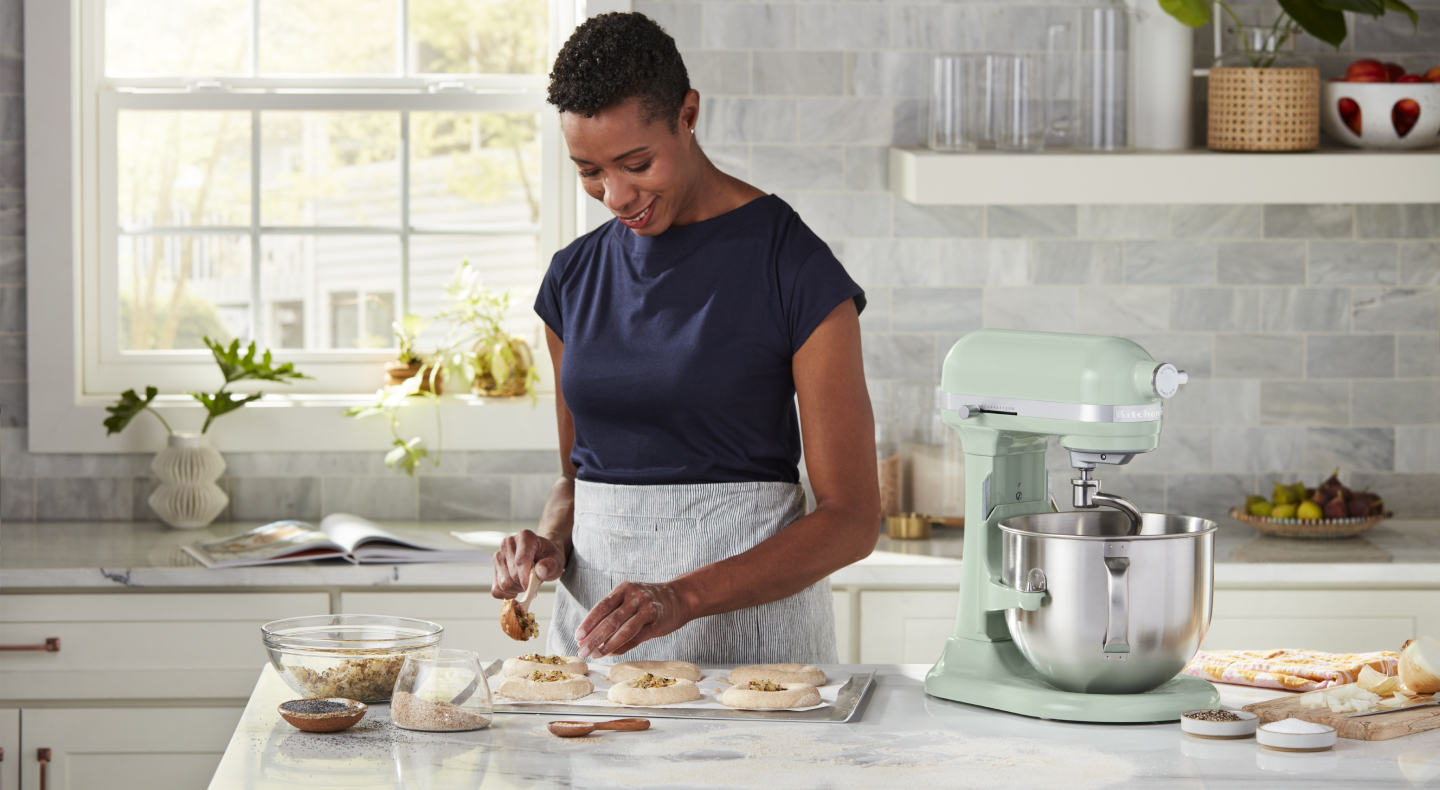 A woman placing filling on pastries for baking A woman placing filling on pastries for baking