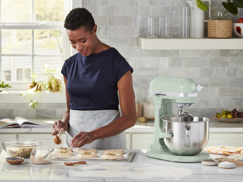 A woman placing filling on pastries for baking A woman placing filling on pastries for baking
