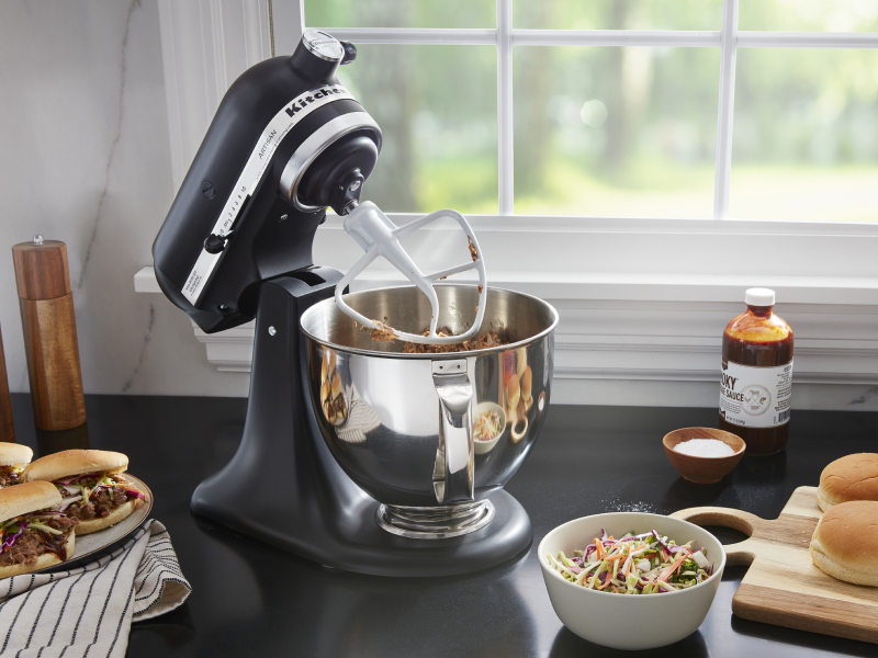 A black tilt-head KitchenAid® stand mixer mixing meat A black tilt-head KitchenAid® stand mixer mixing meat