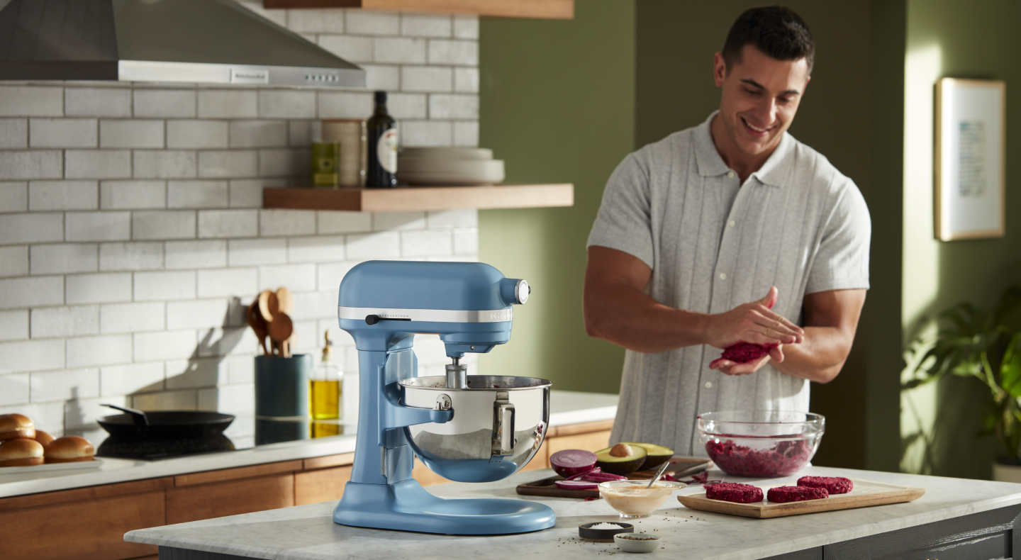 A man flattening patties next to a blue bowl-lift KitchenAid® stand mixer A man flattening patties next to a blue bowl-lift KitchenAid® stand mixer