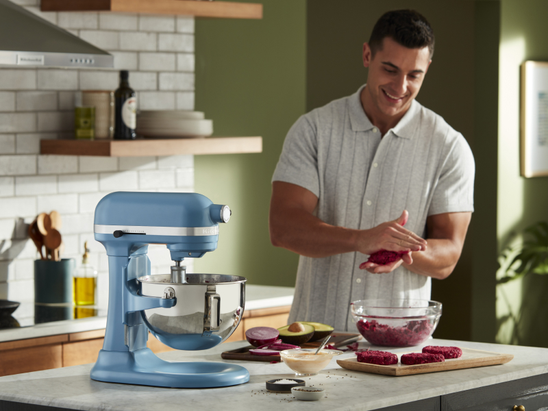 A man flattening patties next to a blue bowl-lift KitchenAid® stand mixer A man flattening patties next to a blue bowl-lift KitchenAid® stand mixer