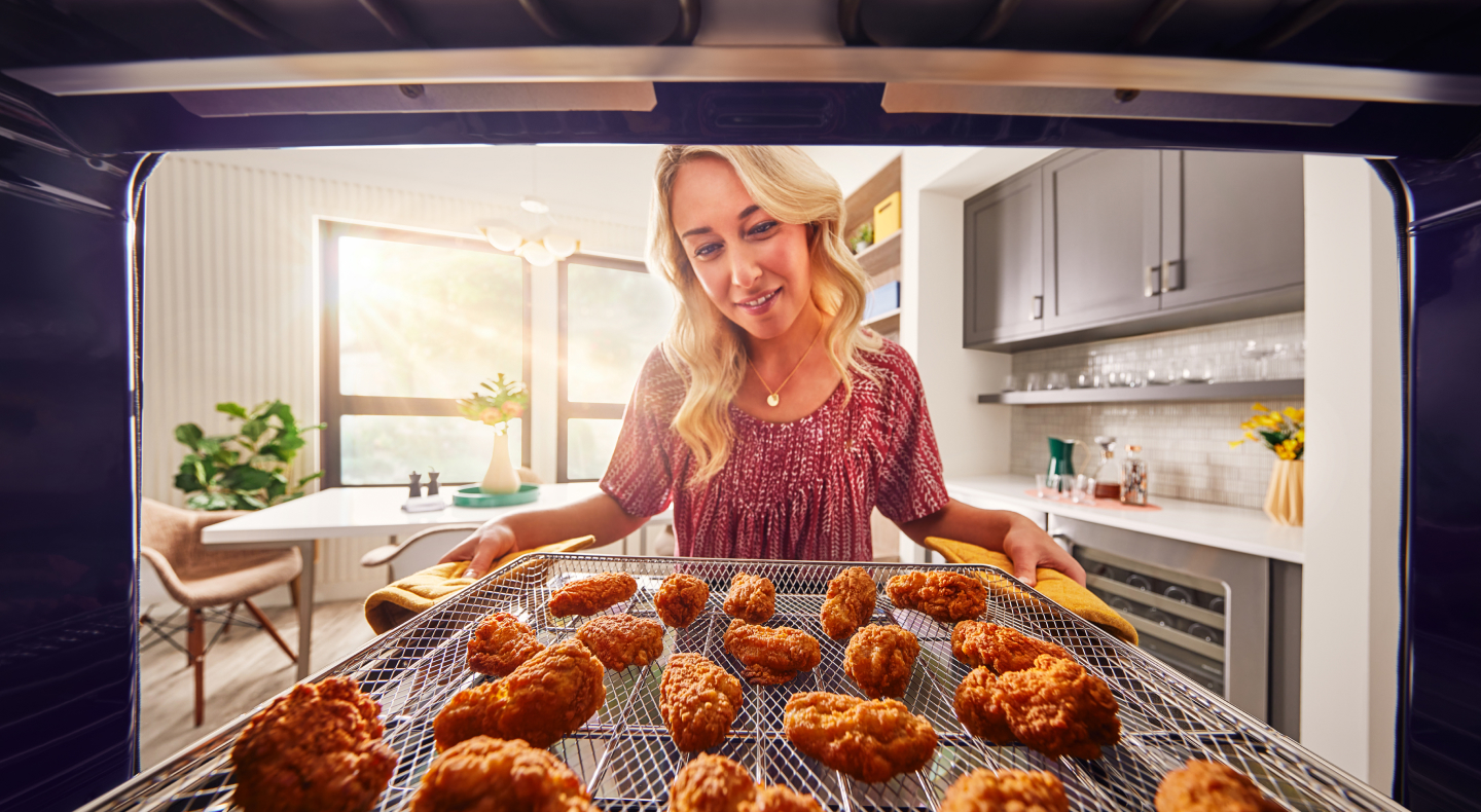 Person pulling out crispy chicken wings from the oven Person pulling out crispy chicken wings from the oven
