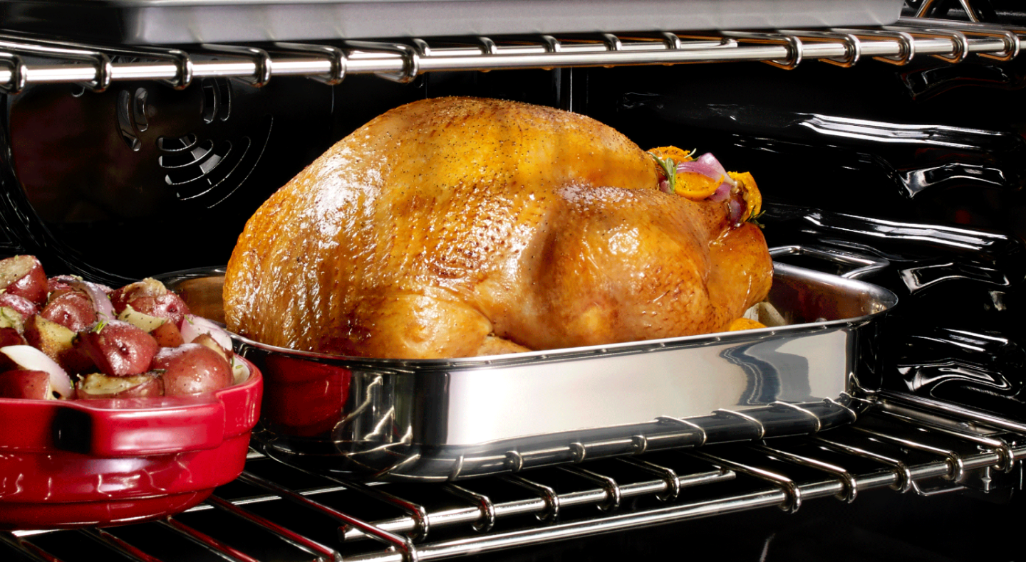 Turkey in an oven next to a casserole dish of red potatoes Turkey in an oven next to a casserole dish of red potatoes