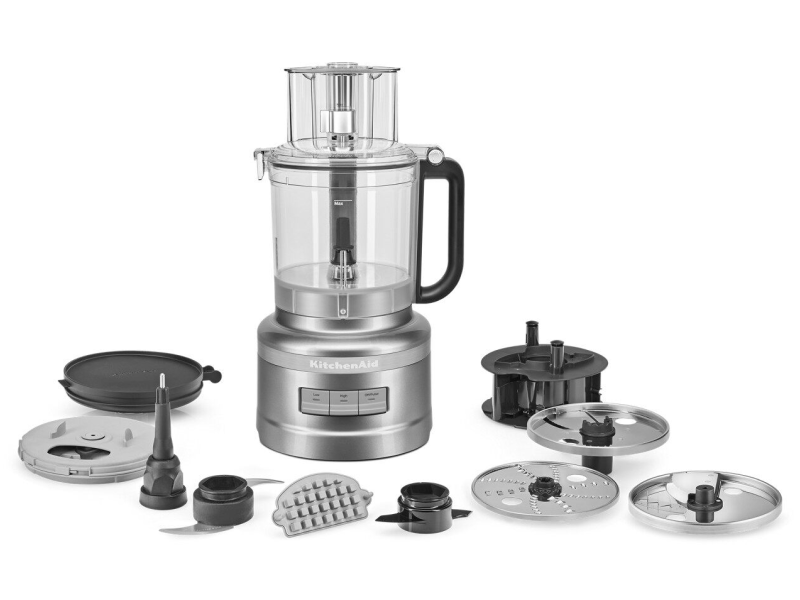 A food processor with its attachments displayed in front it. A food processor with its attachments displayed in front it.