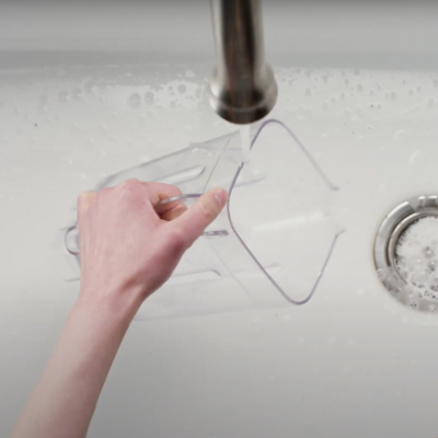 Hand holding KitchenAid® blender jar under the faucet over sink of soapy water