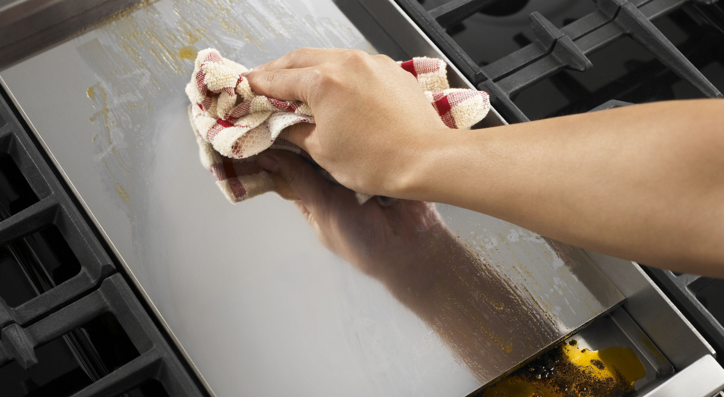 Person wiping griddle with clean dish rag Person wiping griddle with clean dish rag