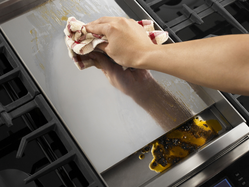 Person wiping griddle with clean dish rag Person wiping griddle with clean dish rag