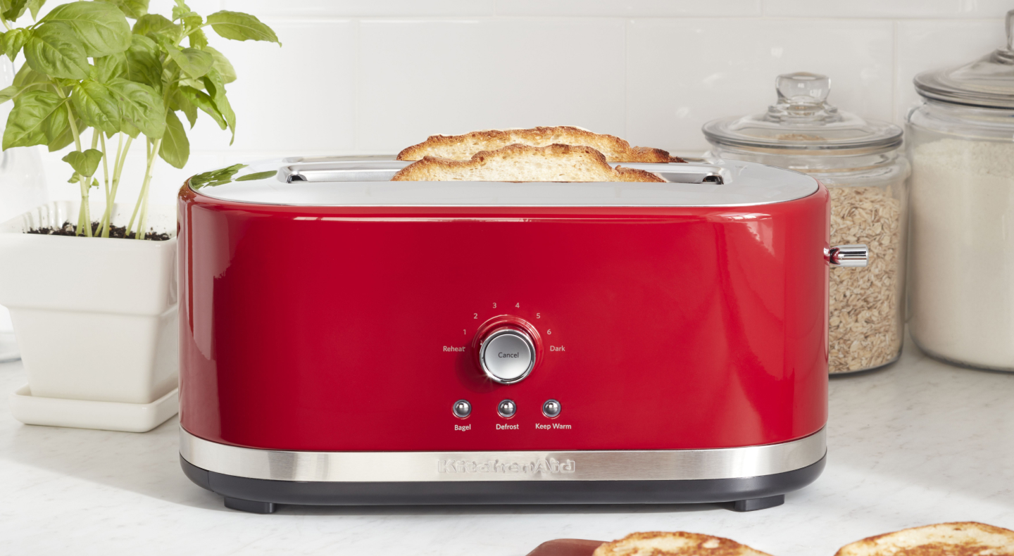 Slices of bread in a red KitchenAid® toaster on a modern kitchen counter. Slices of bread in a red KitchenAid® toaster on a modern kitchen counter.