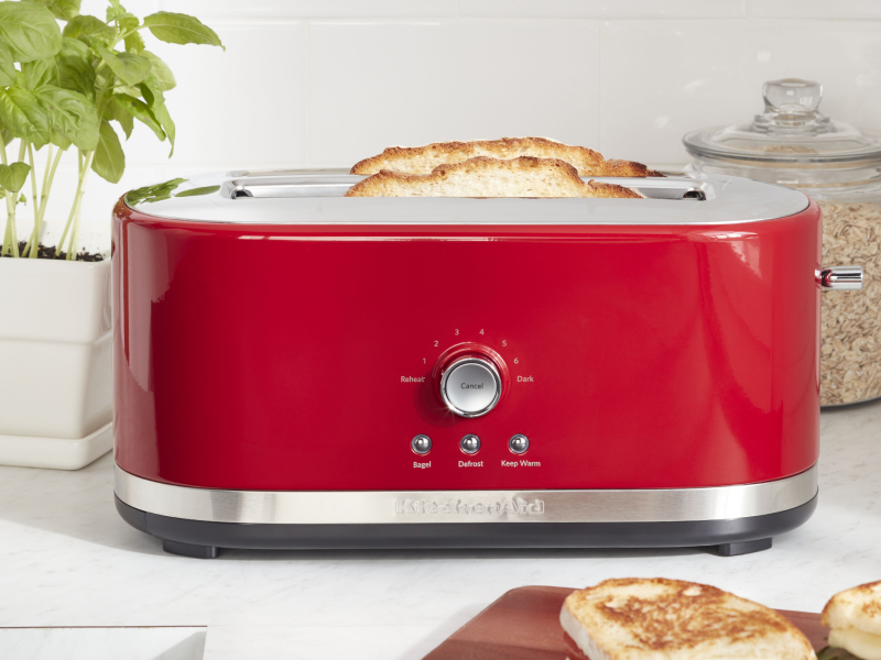 Slices of bread in a red KitchenAid® toaster on a modern kitchen counter. Slices of bread in a red KitchenAid® toaster on a modern kitchen counter.