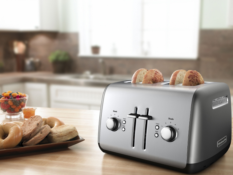 Bagel slices in a silver 4-slice KitchenAid® toaster on a modern kitchen counter. Bagel slices in a silver 4-slice KitchenAid® toaster on a modern kitchen counter.