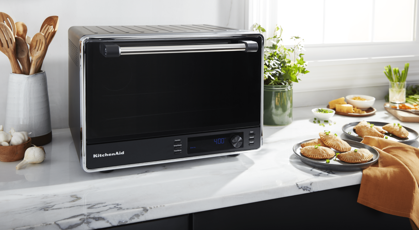 A black KitchenAid® air fryer and fresh empanadas on a countertop A black KitchenAid® air fryer and fresh empanadas on a countertop