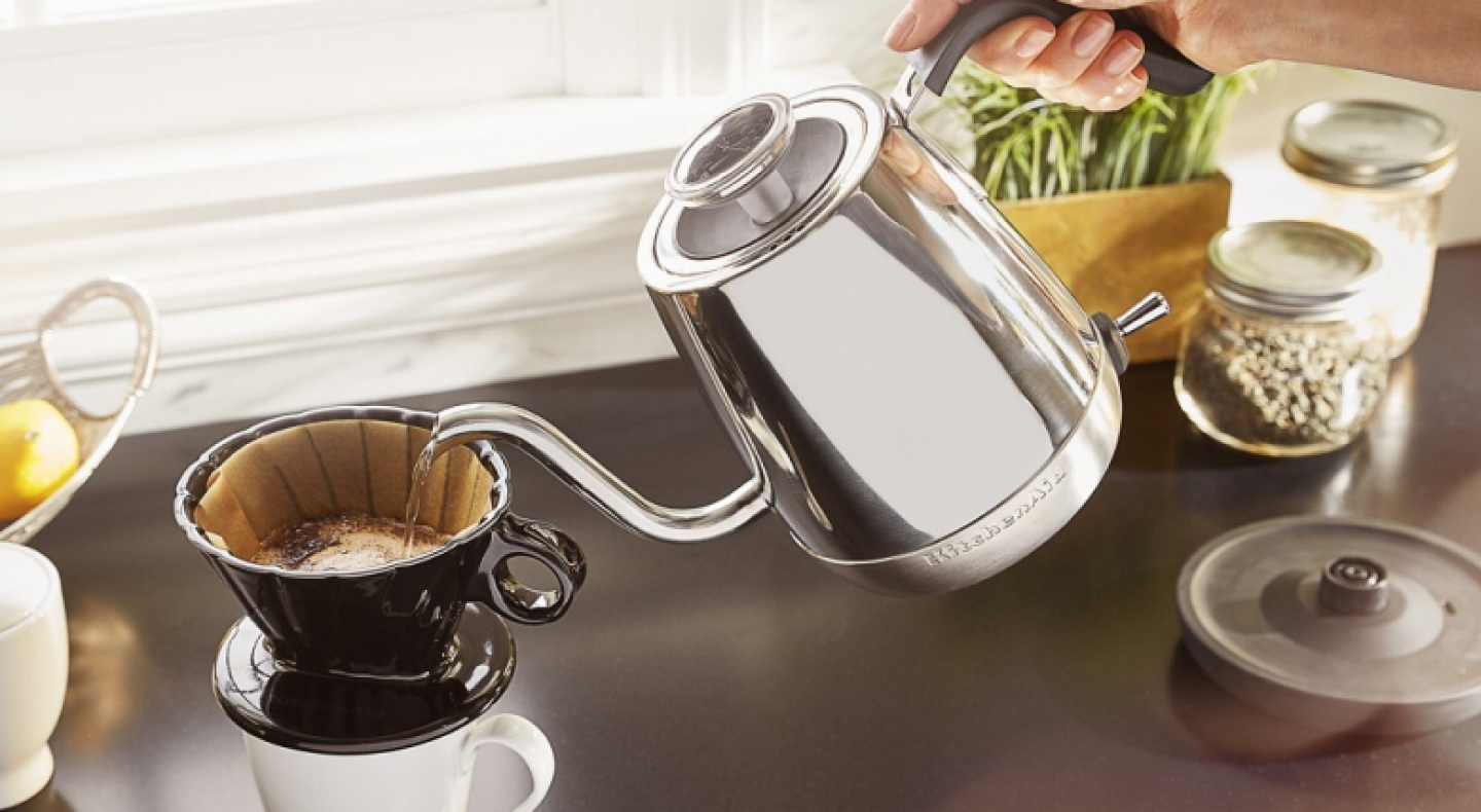 A woman pouring hot water from a KitchenAid® electric kettle into a pour-over coffee mug A woman pouring hot water from a KitchenAid® electric kettle into a pour-over coffee mug