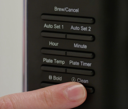 Woman starting cleaning cycle on coffee machine