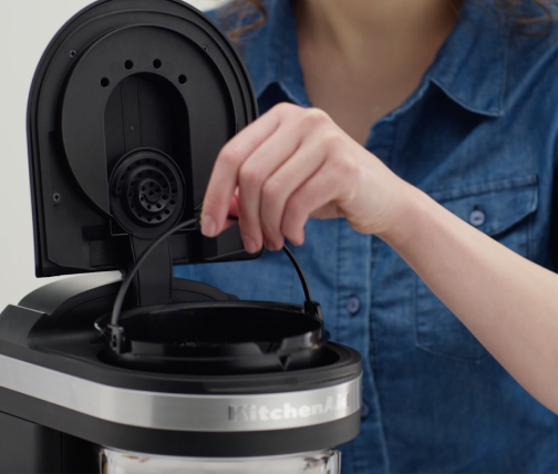 Woman replacing water filter in coffee maker
