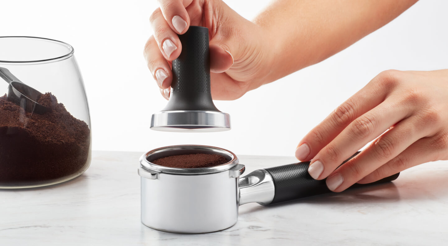 Hand tamping coffee grounds into portafilter Hand tamping coffee grounds into portafilter